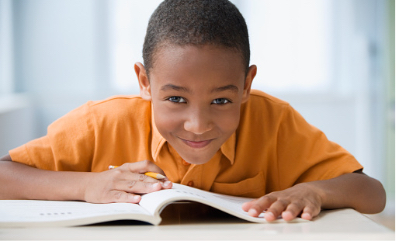Young boy smiling at camera with an open book