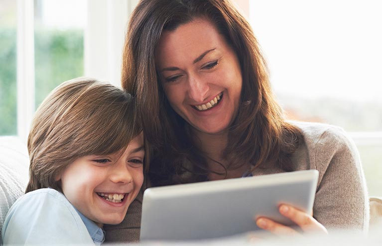 Young boy with mom looking at a tablet smiling