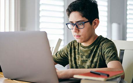 Young boy focusing and looking at laptop