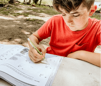 Young boy writing on Beast Academy guide book